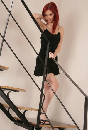 Natural redhead removes a black dress and panties to get naked on a staircase #1